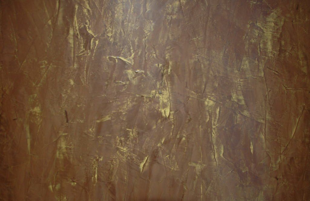 A close up of a brown wall with gold paint on it.