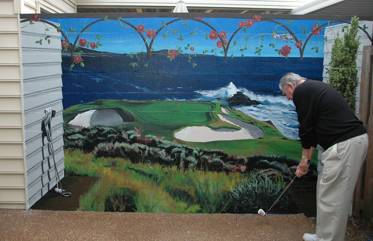 A man is playing golf in front of a painting of a golf course