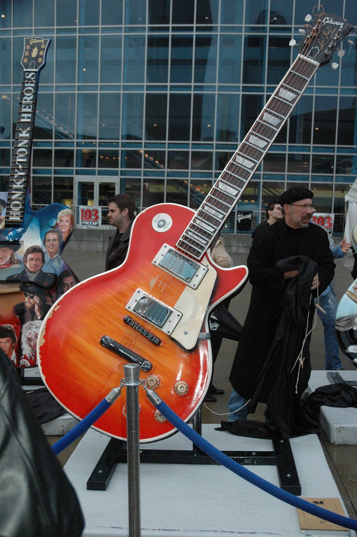 A large red guitar is on display in front of a building