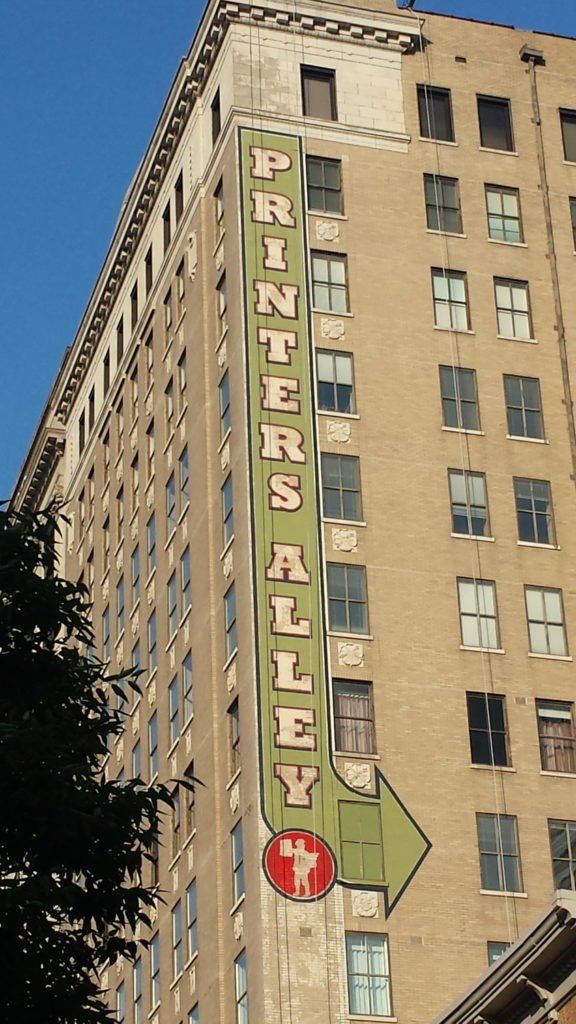 A tall building with a sign that says printers alley