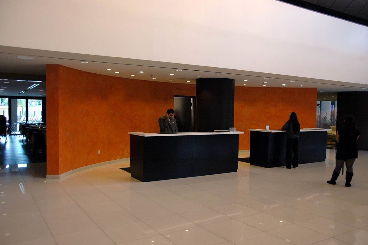 A man sitting at a desk in a lobby talking on a cell phone