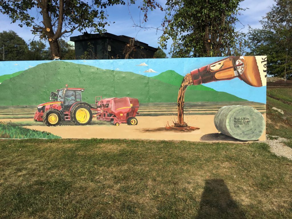 A painting of a tractor and a bale of hay on a wall.