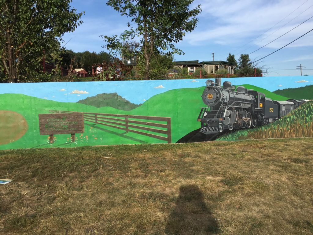A painting of a train on a wall in a field.