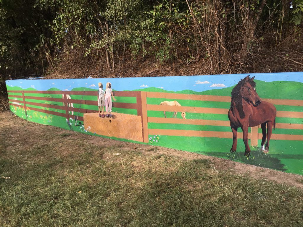 A painting of a horse and a fence on a wall.