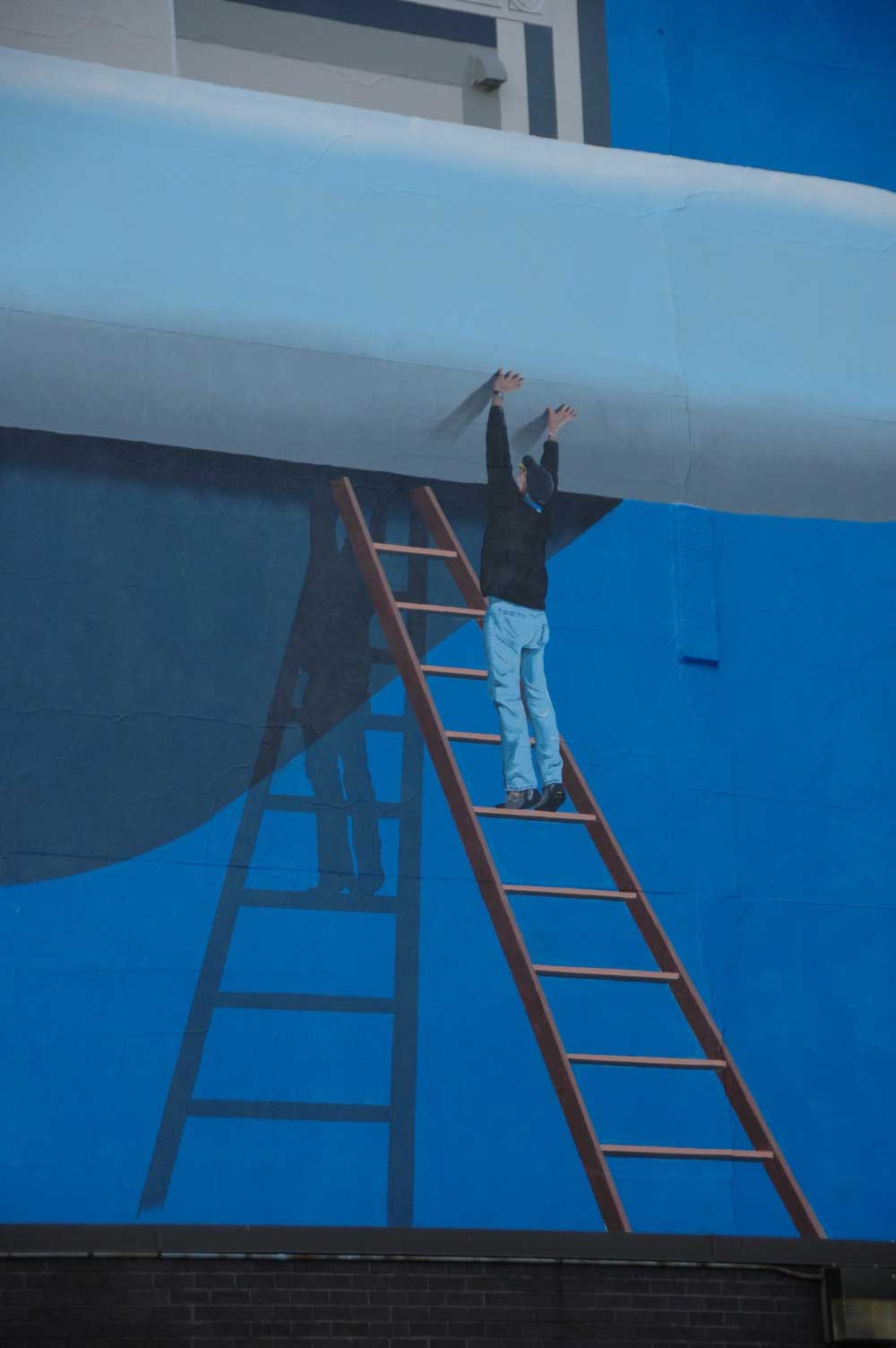 A man is climbing up a ladder on a blue wall