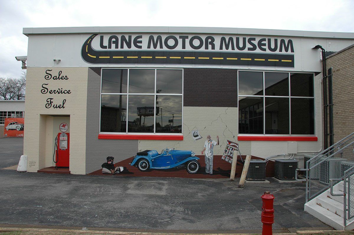 A white building with a sign that says lane motor museum