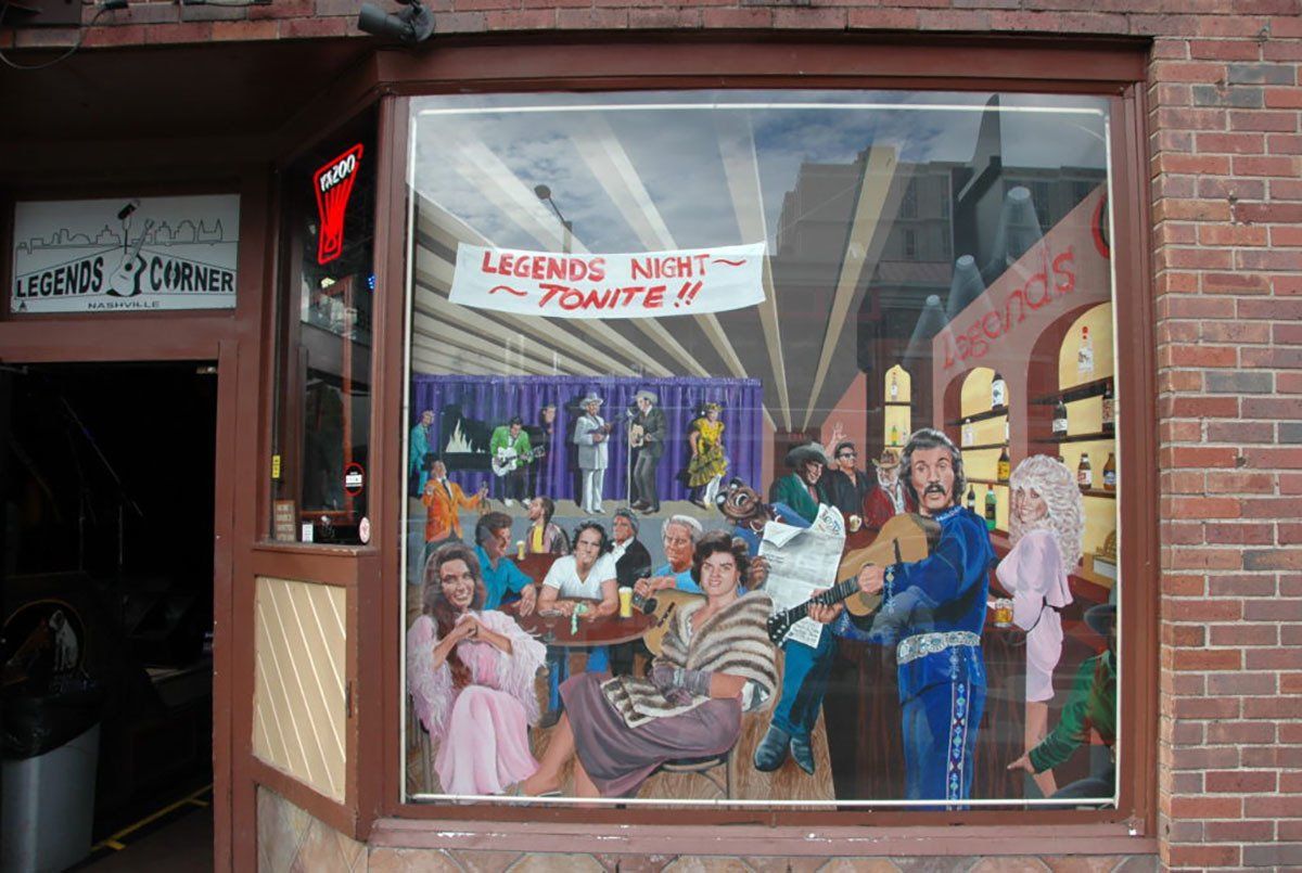 A window with a painting of a group of people sitting at tables