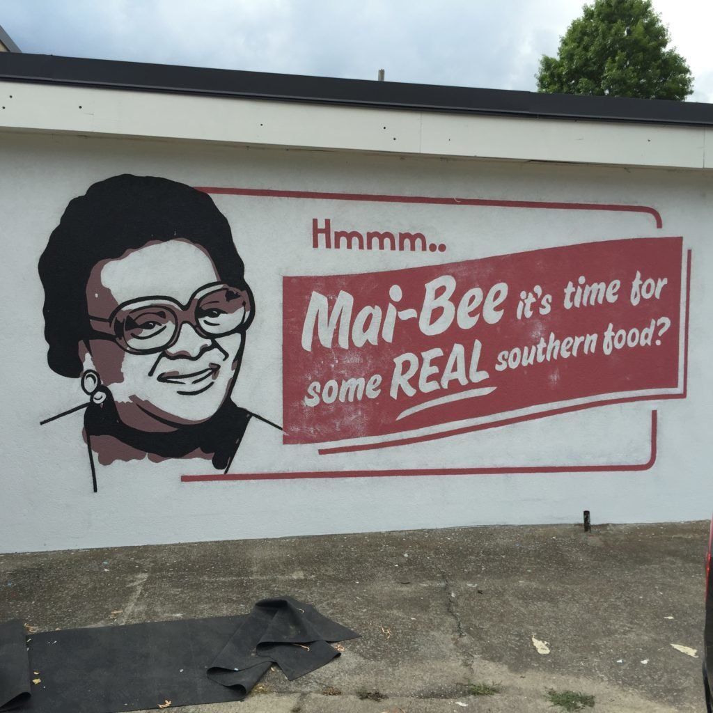 A mural of a smiling woman says mai-bee it 's time for some real southern food