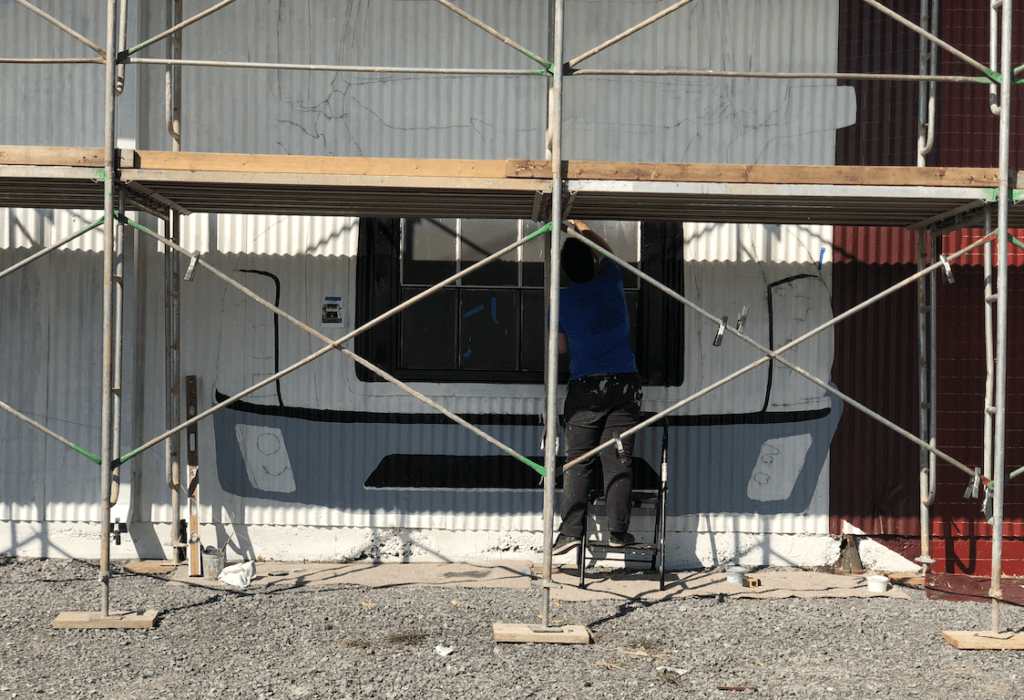 A man is painting a building with scaffolding around it
