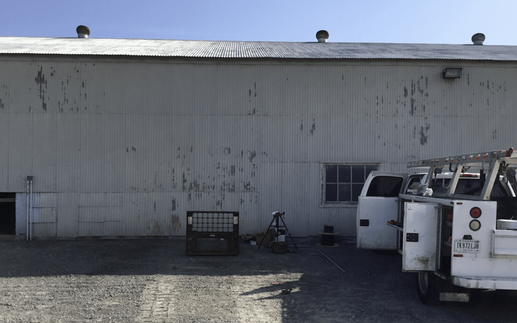 A white truck is parked in front of a white building