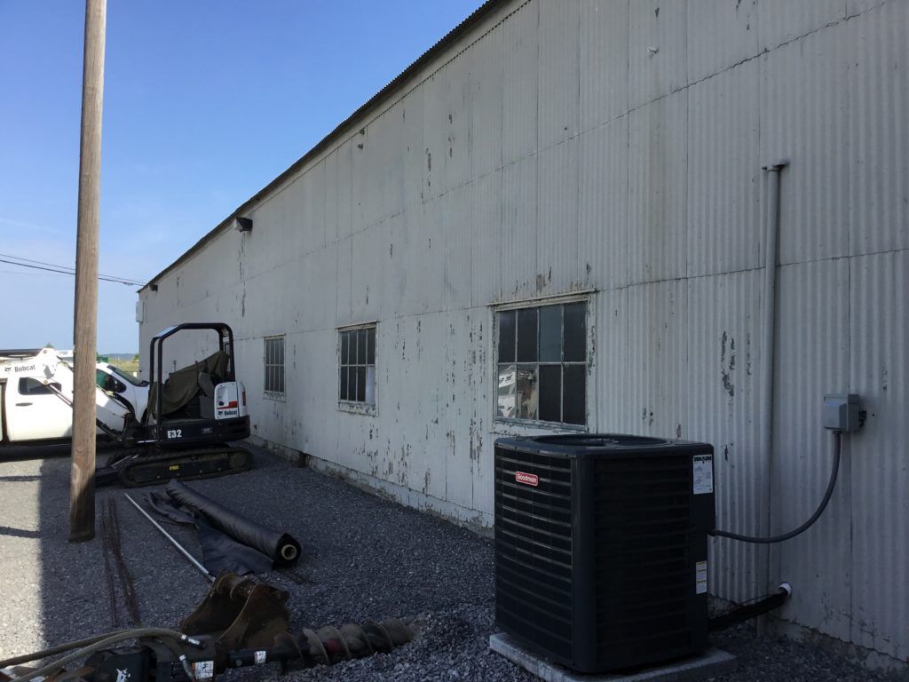 A white building with a black air conditioner on the side