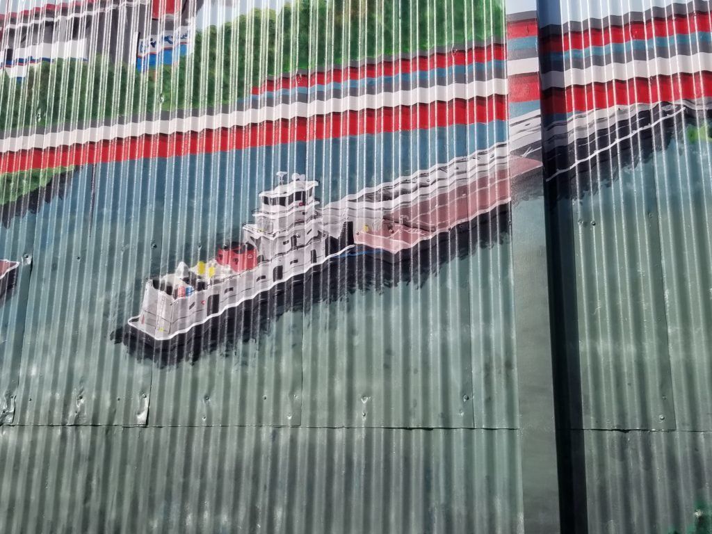A painting of a ship in the water on a fence.