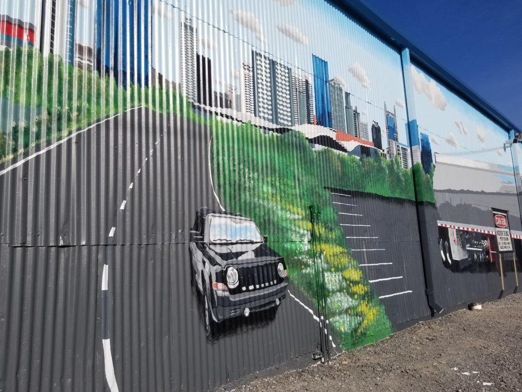 A jeep is driving down a road in a painting on a wall.