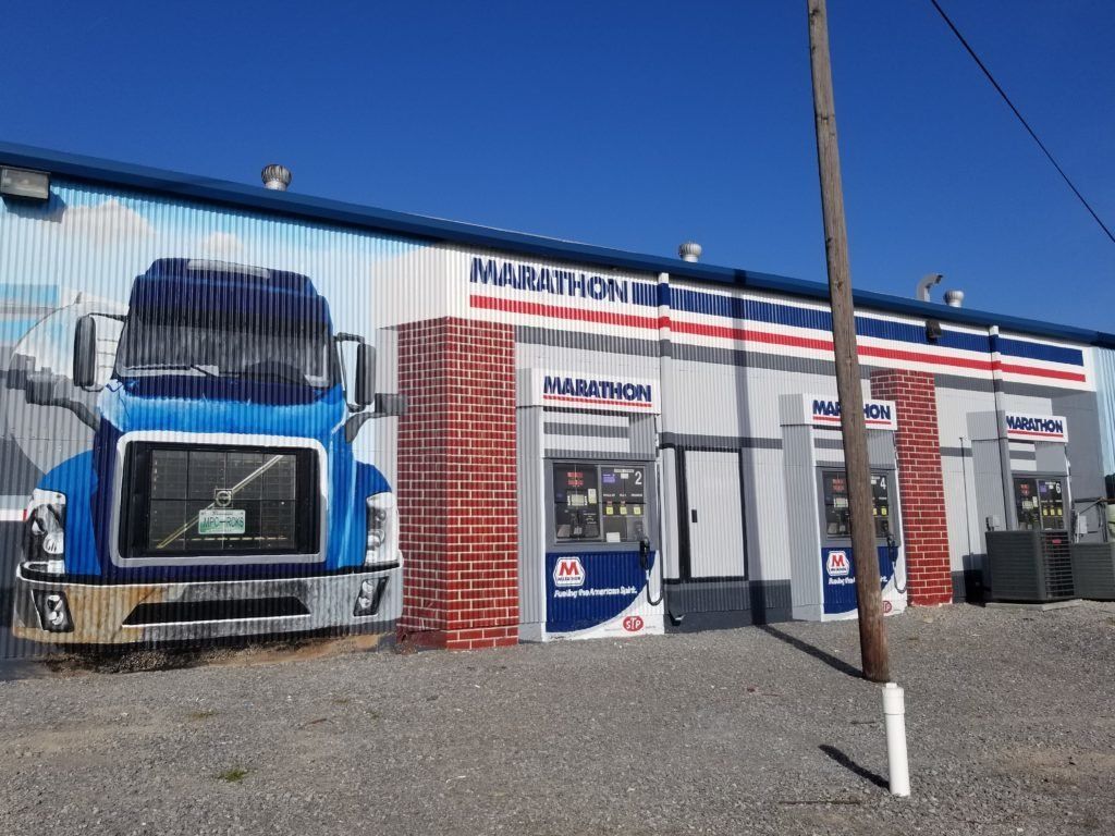 A truck is painted on the side of a building that says marathon