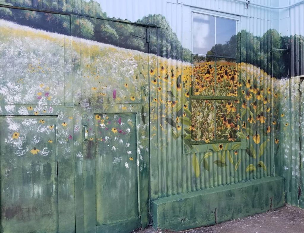 A wall with a painting of a field of sunflowers on it