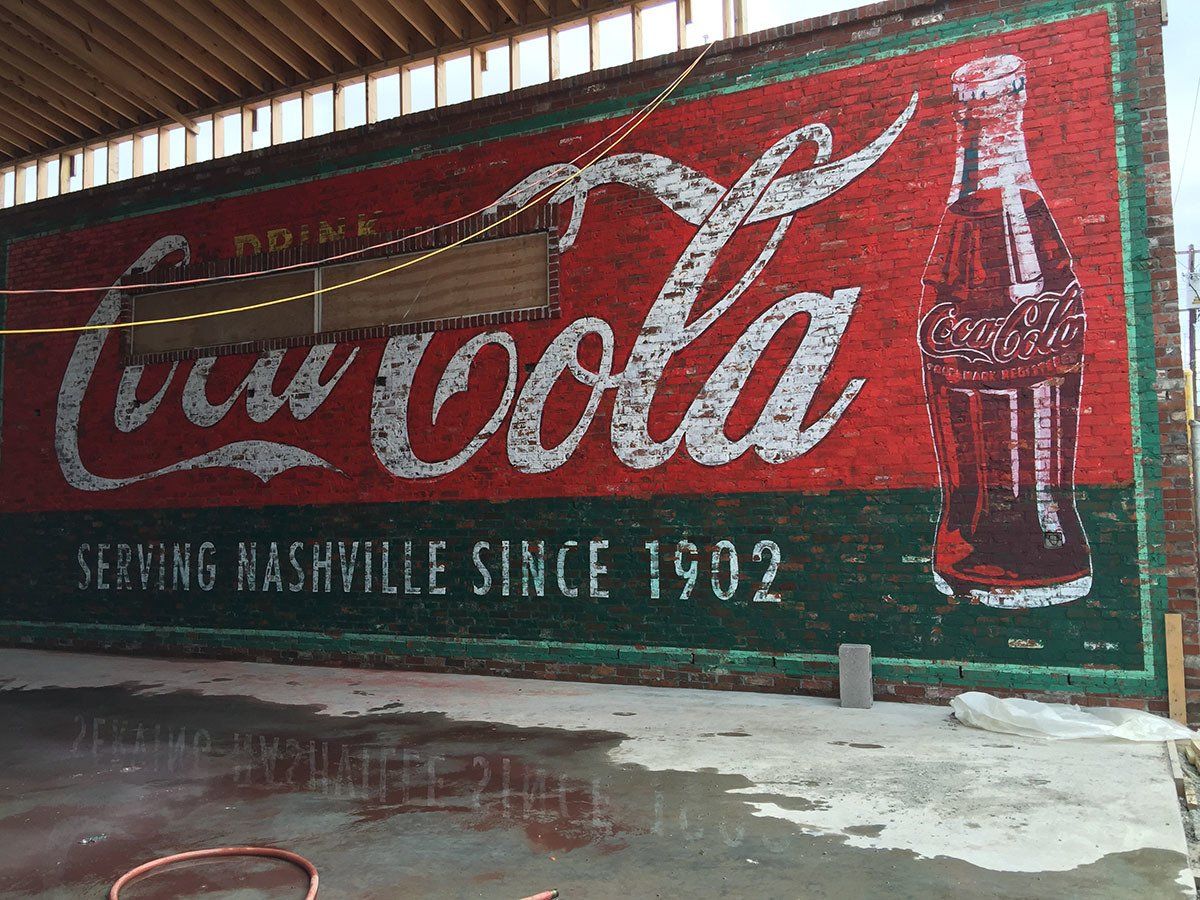 A large coca cola sign on a brick wall