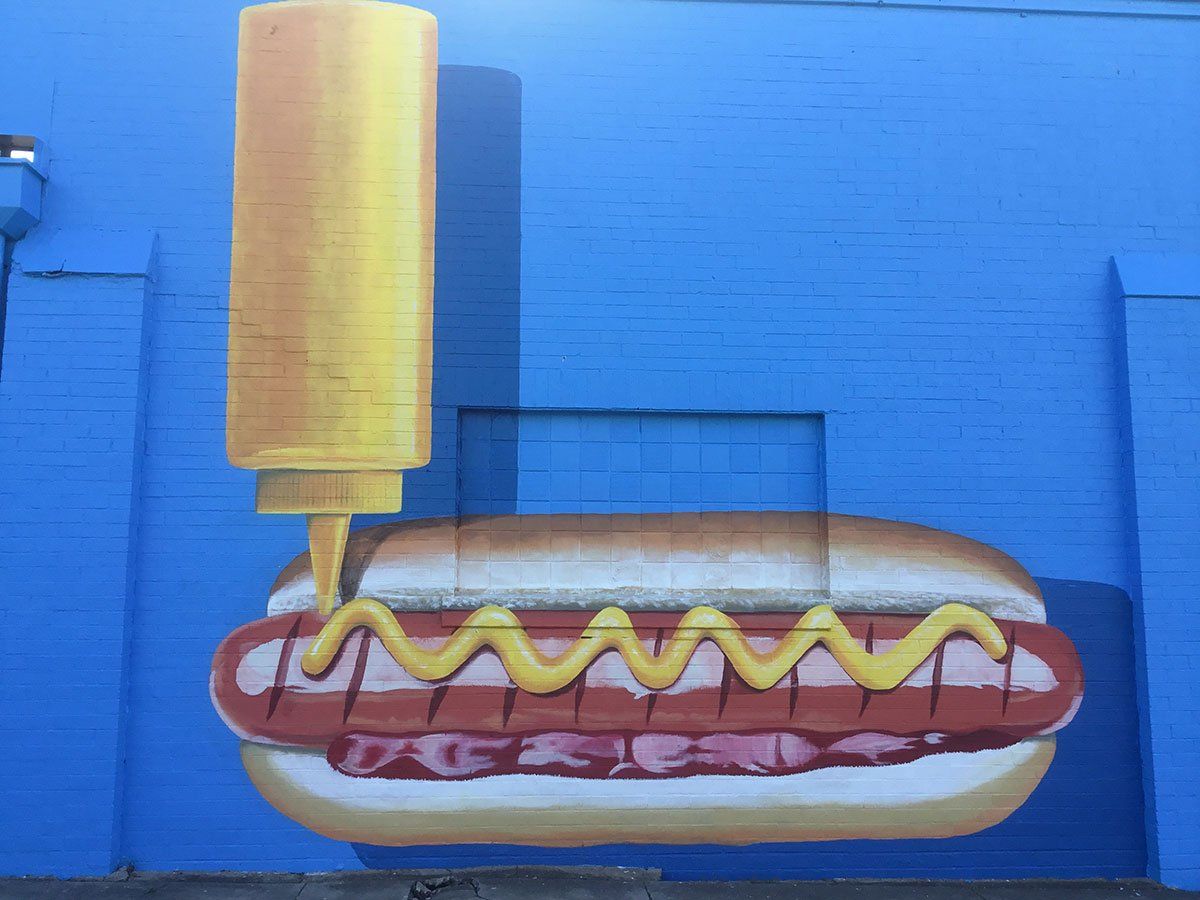 A painting of a hot dog with mustard on it