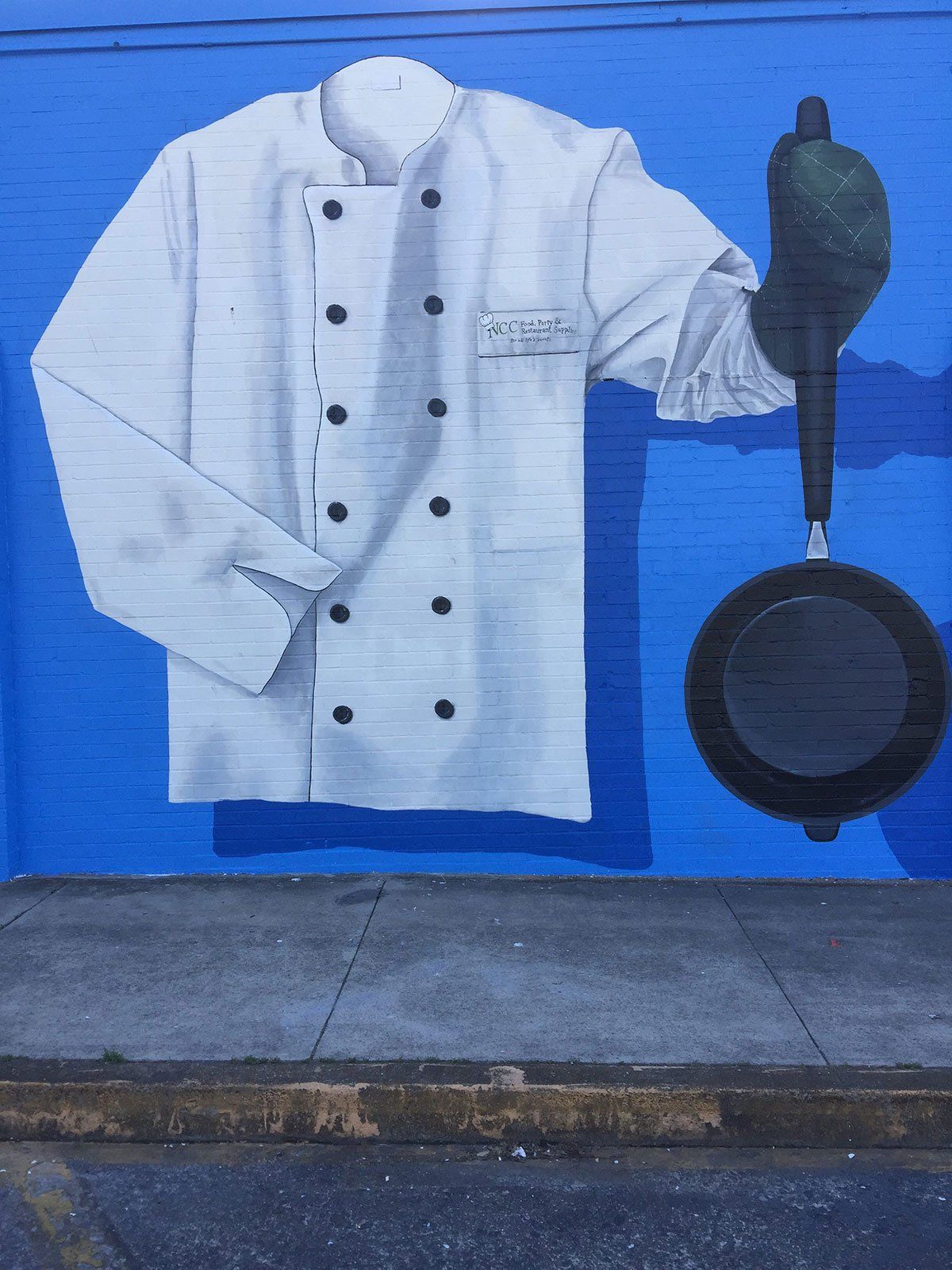 A mural of a chef 's jacket and pan on a blue wall