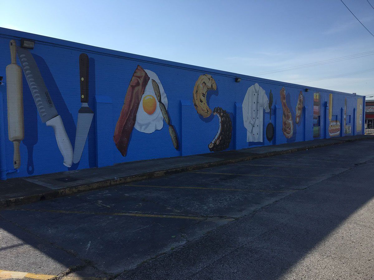 A large blue wall has a mural of various food items on it
