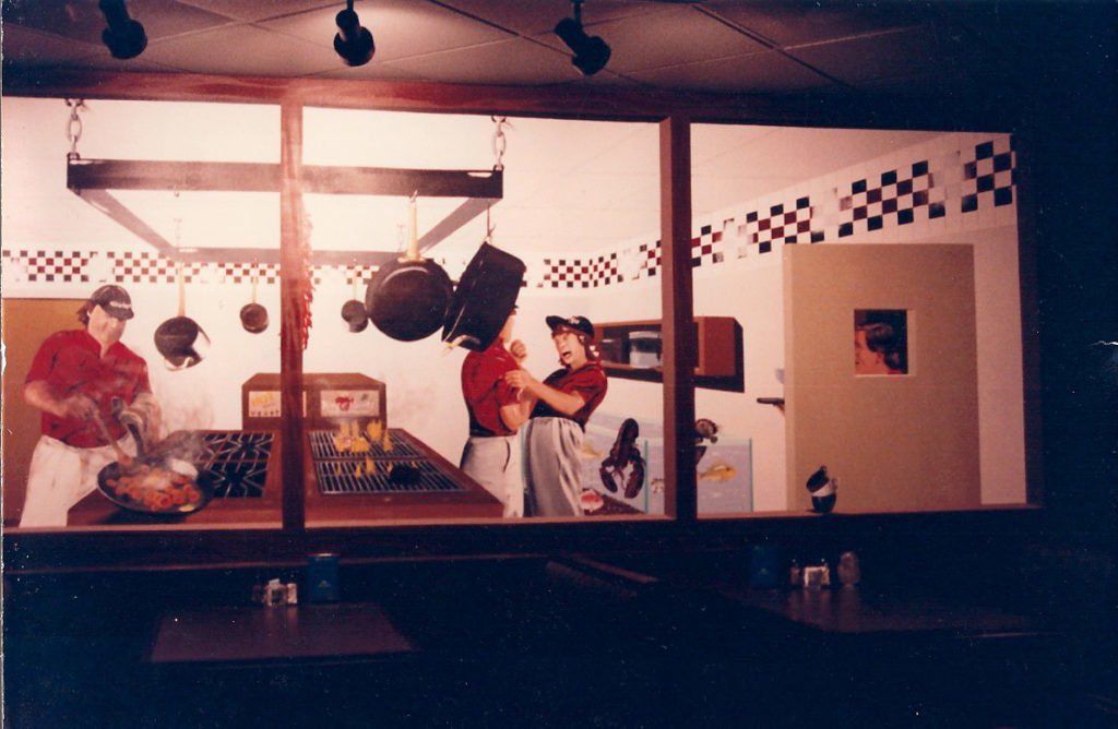 A painting of people in a kitchen with checkered tiles on the wall