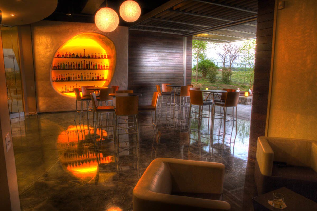 A living room with a couch , chairs , tables and a bar.