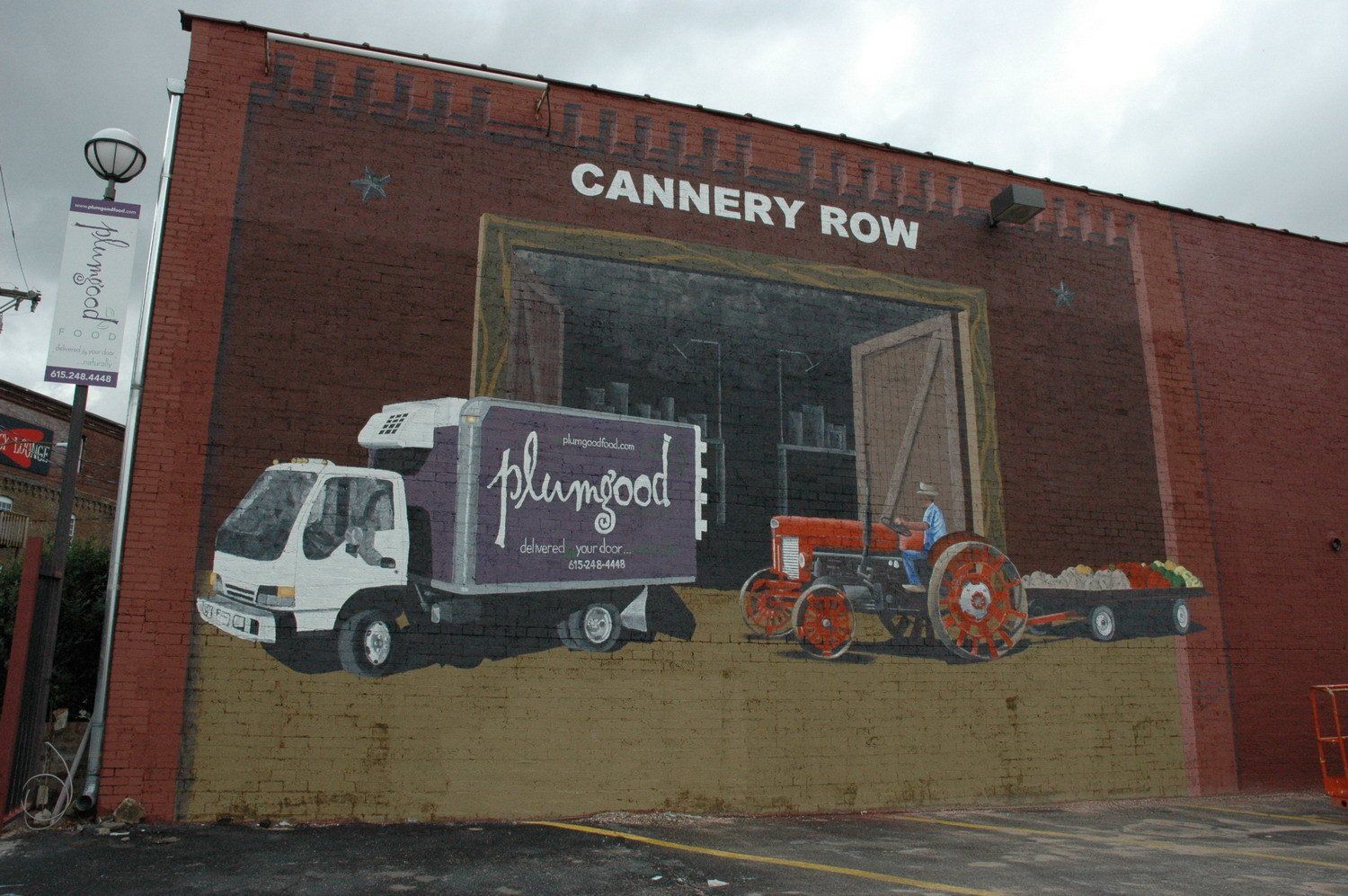 A cannery row building with a painting of a truck and tractor