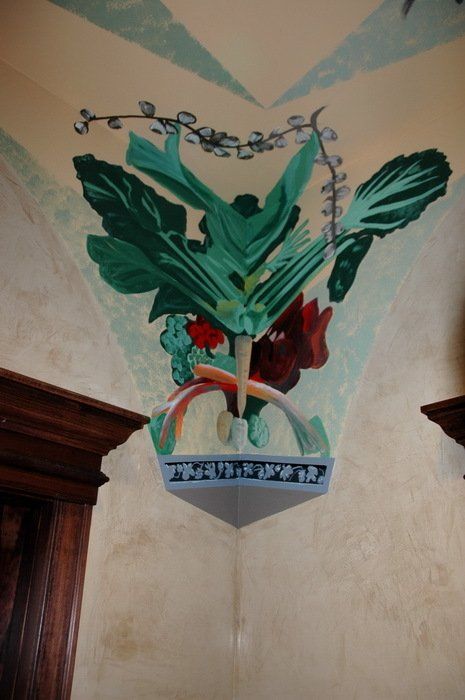 A corner of a wall with a painting of vegetables on it