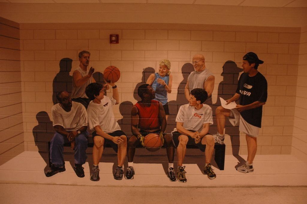 A group of people are sitting on a bench with a basketball.