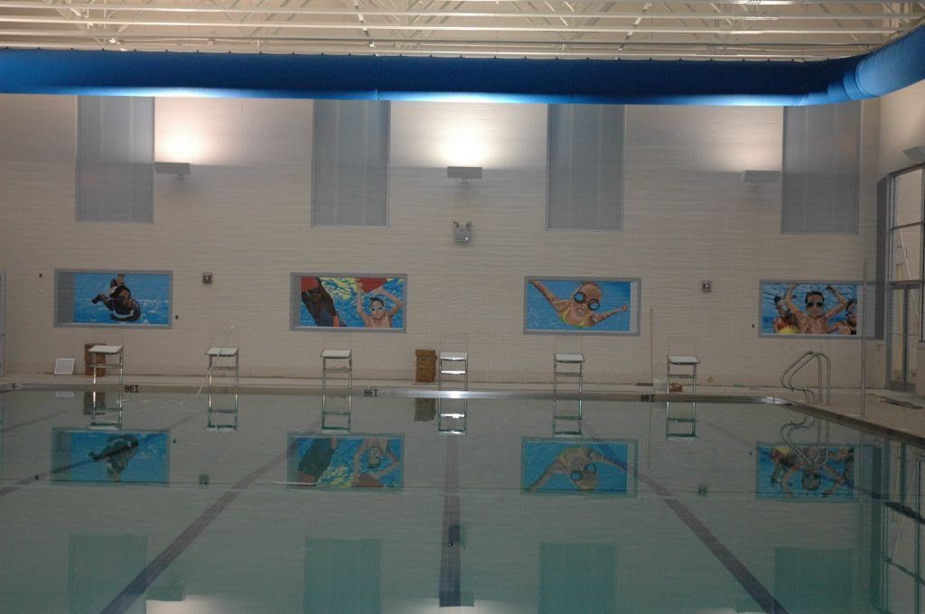A large indoor swimming pool with paintings on the wall