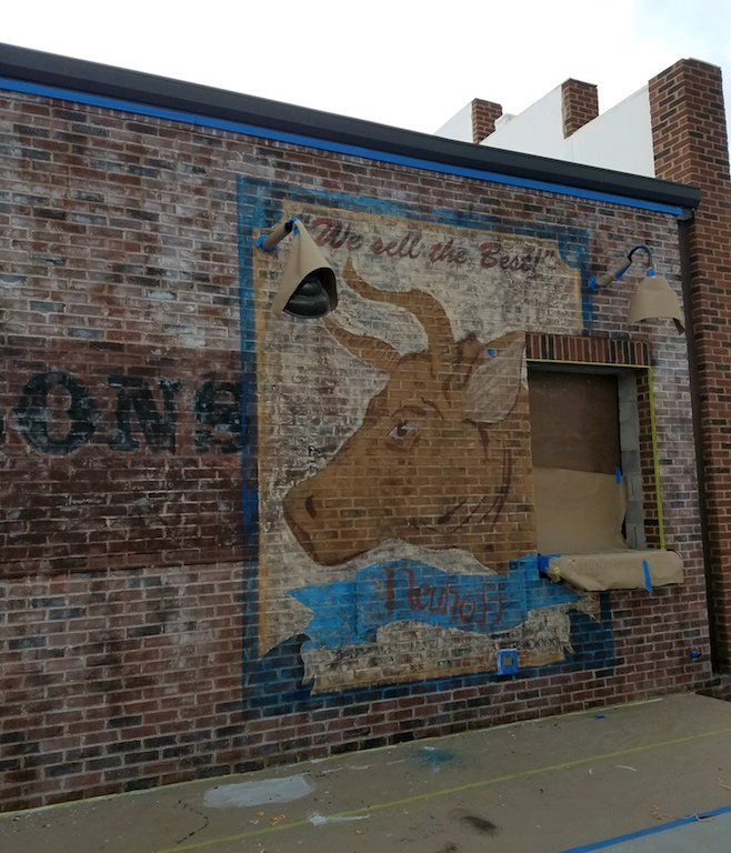 A brick wall with a painting of a bull on it