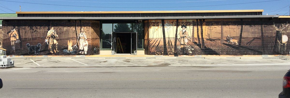 A car is parked in front of a building with a mural on the side of it.