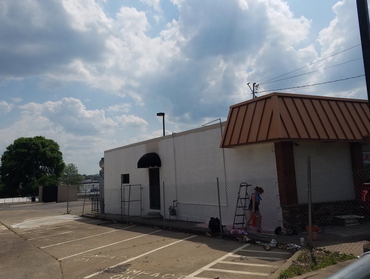 A white building with a brown roof is being painted