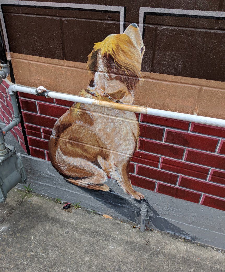 A painting of a dog on a brick wall next to a pipe.