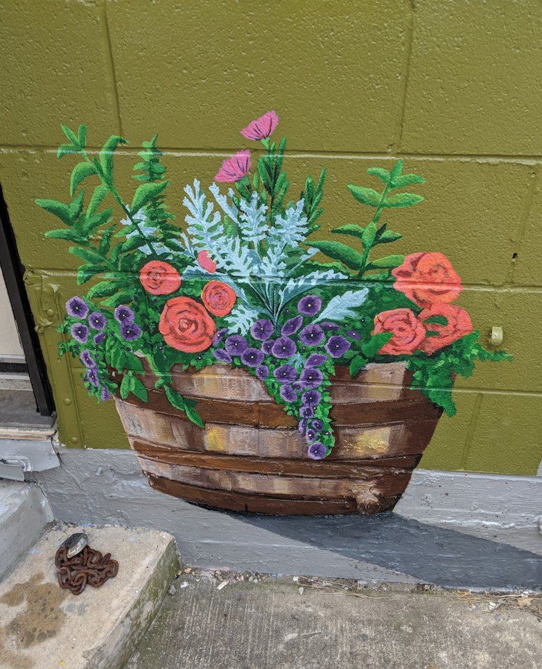A painting of a basket filled with flowers on a wall.