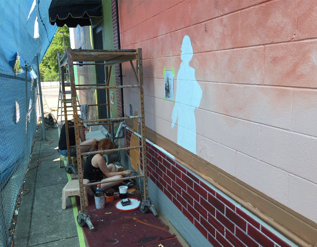 A man is painting a picture on the side of a building