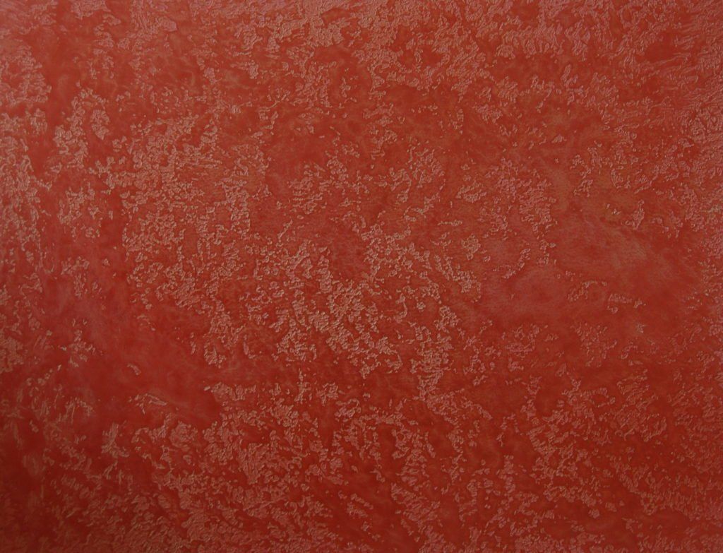 A close up of a red wall with a texture.