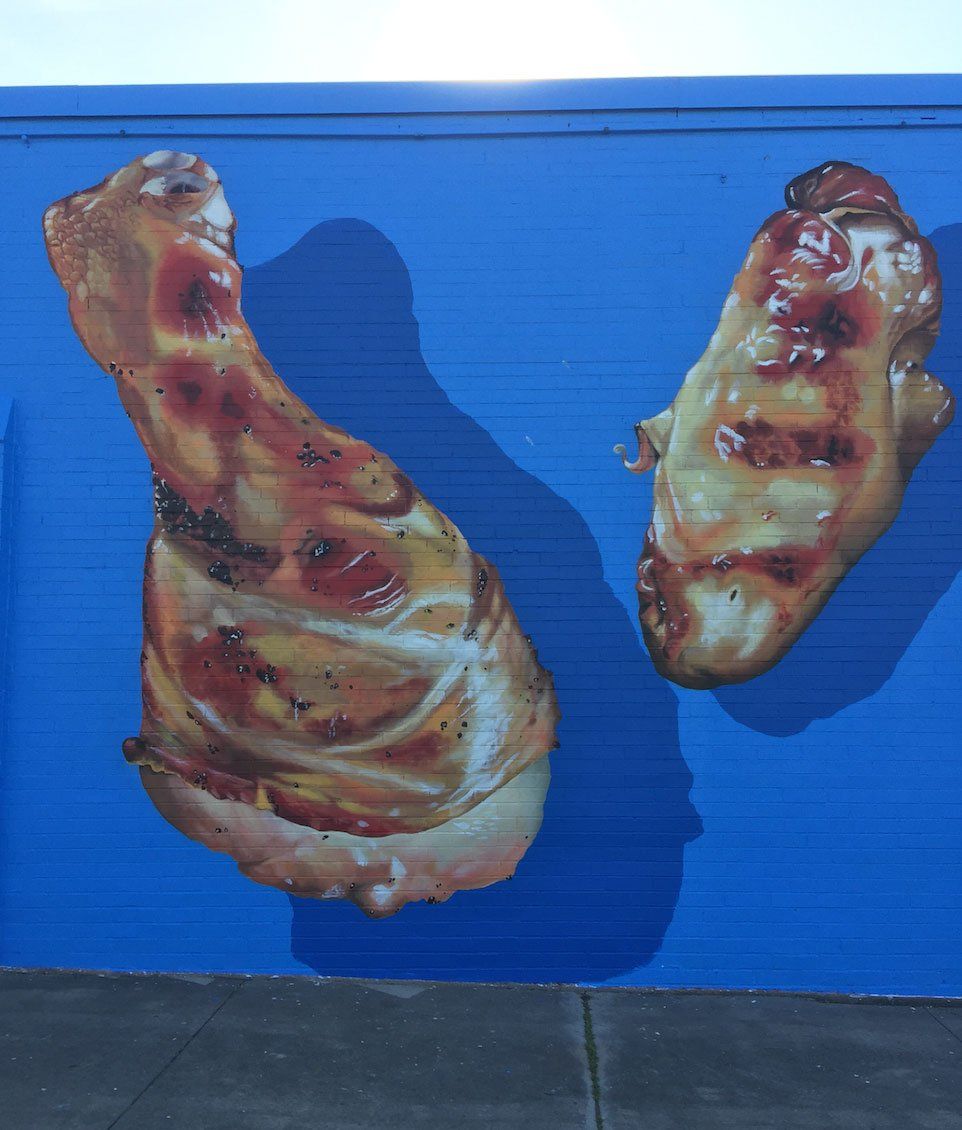 Two chicken legs are painted on a blue wall