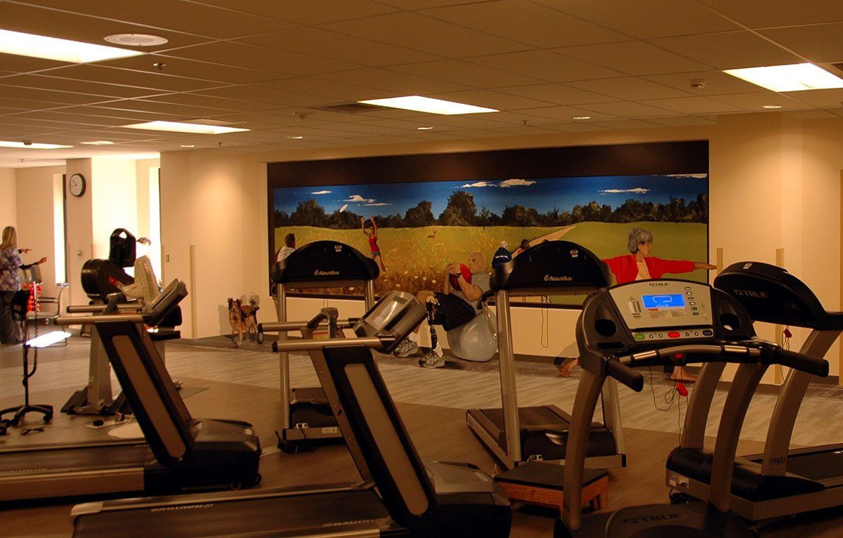 A gym with treadmills and a painting on the wall
