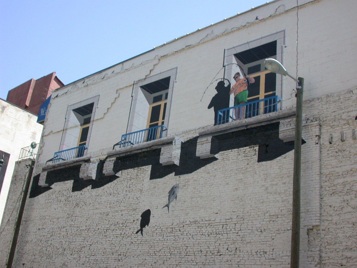 A couple standing on a balcony on the side of a building