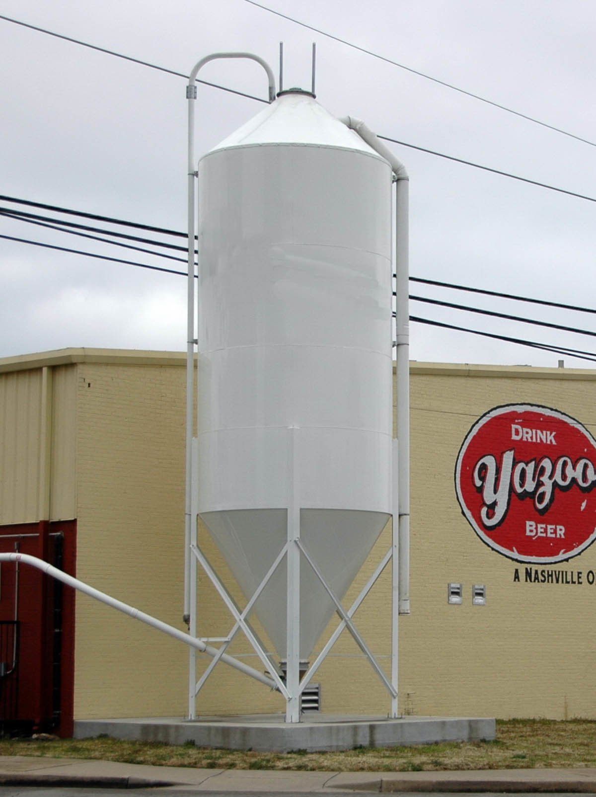 A large white silo sits in front of a building that says yazoo