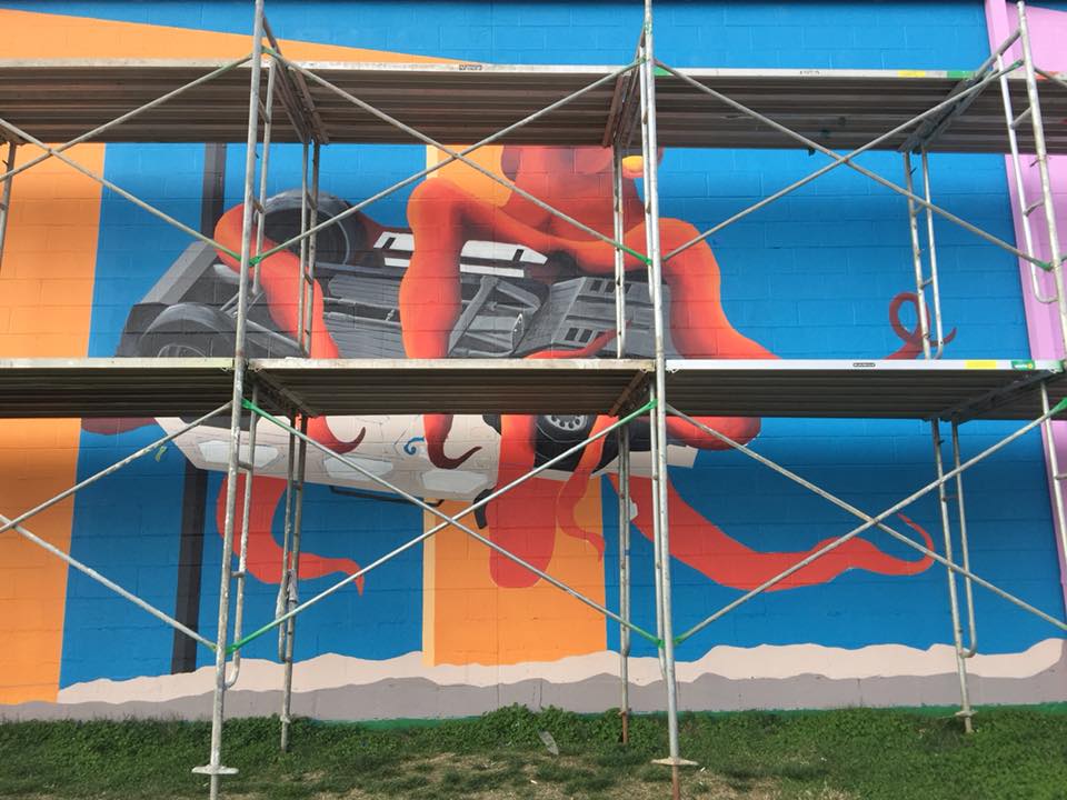 A mural is being painted on the side of a building