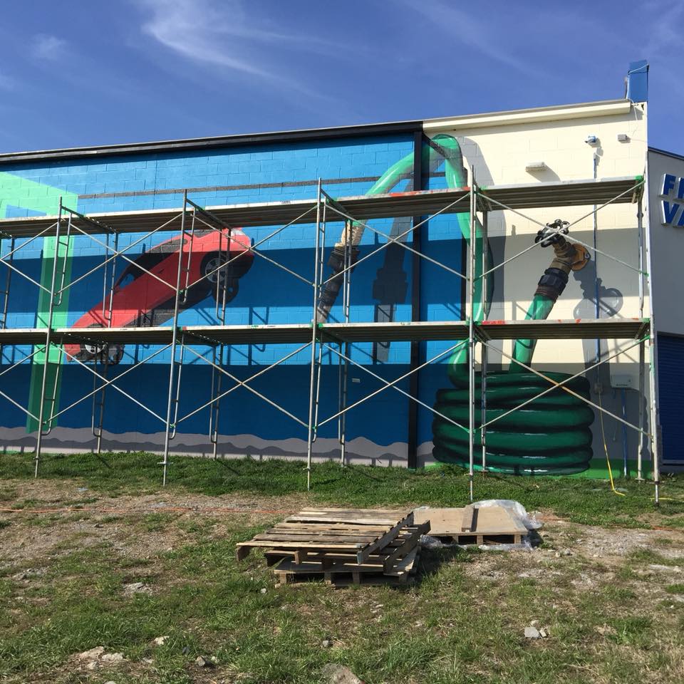 A mural is being painted on the side of a building