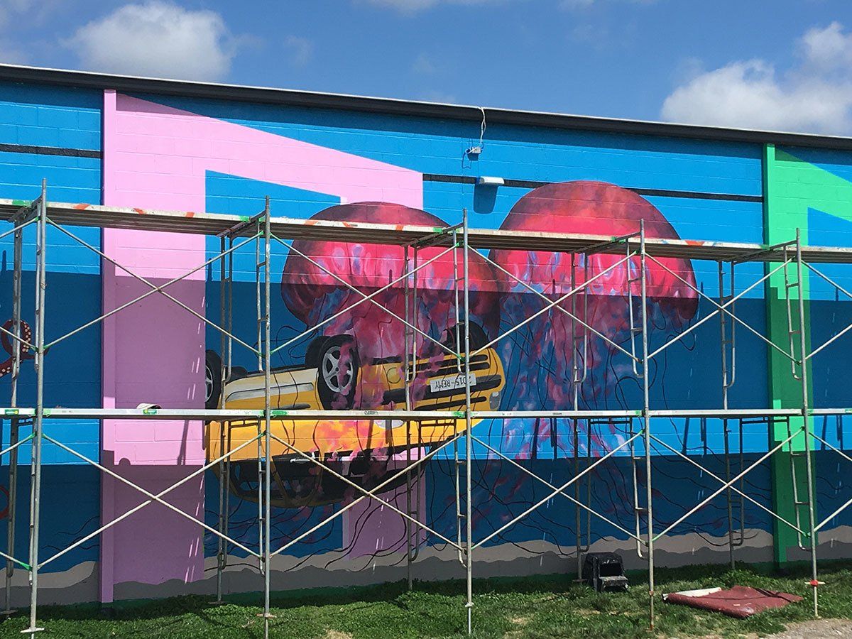 A large mural is being painted on the side of a building.