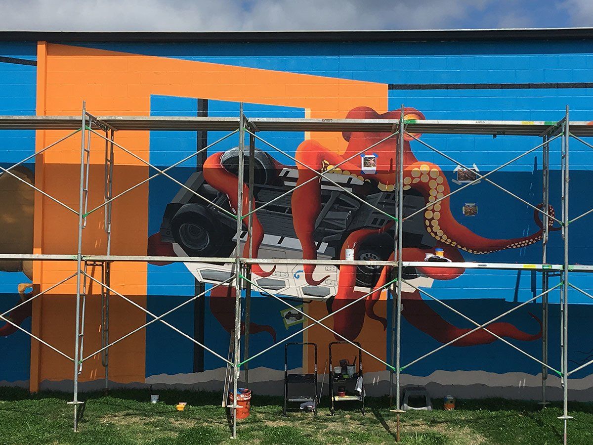 A large mural is being painted on the side of a building.