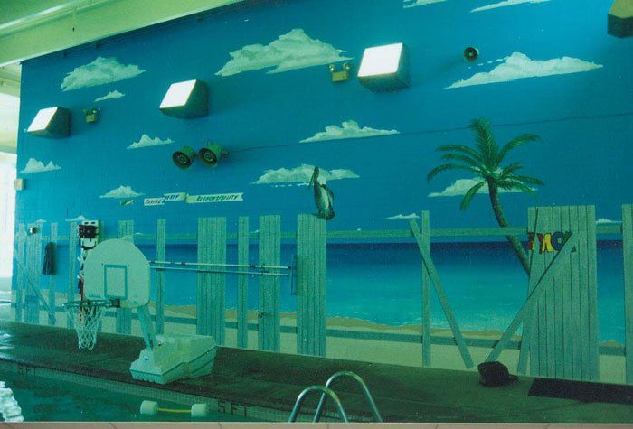A swimming pool with a mural of a beach on the wall.