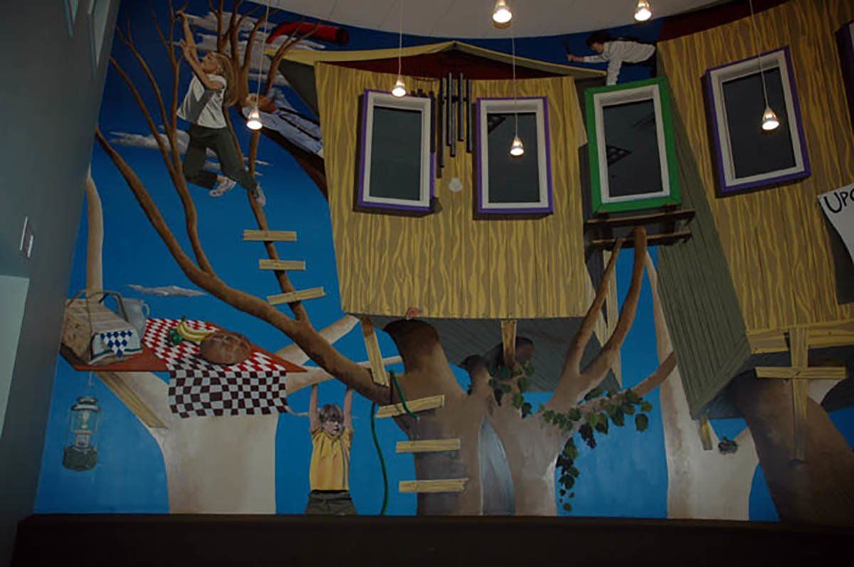 There is a painting of a tree house on the wall.