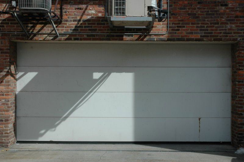 A white garage door is open on a brick building.