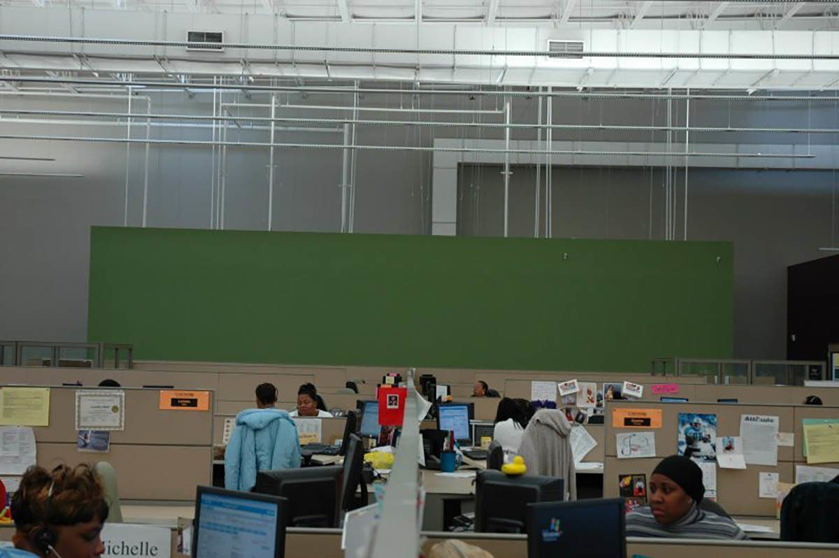 A group of people are sitting in cubicles in an office