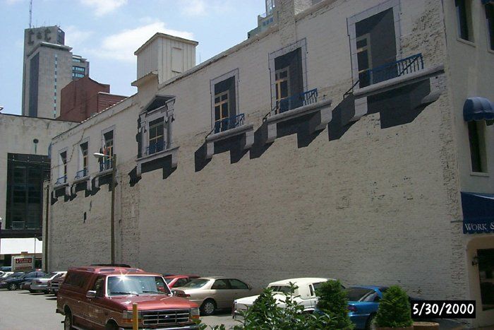 A red van is parked in front of a white building