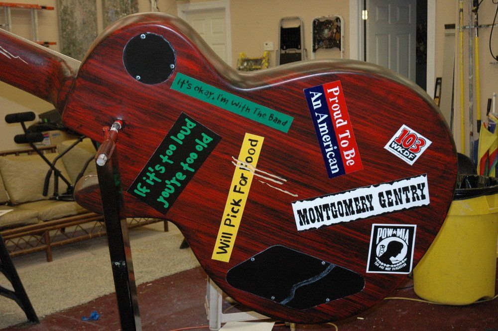 A guitar with stickers on it including one that says proud to be an american